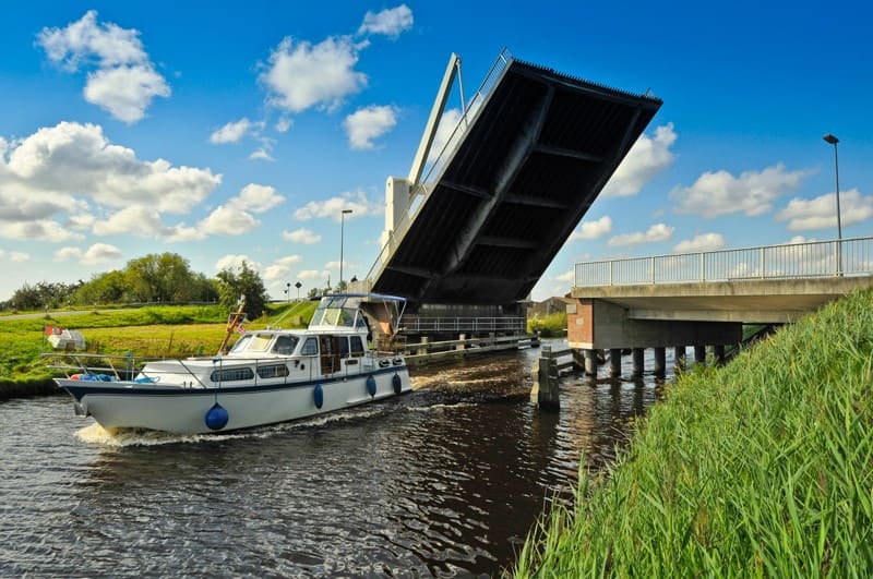 Boot, das unter einer Brücke durchfährt in der Gemeinde Ihlow
