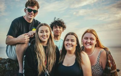 Fünf Jugendliche, die zusammenstehen und in die Kamera lachen