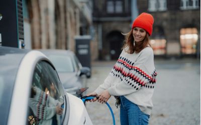 Eine junge Frau lädt ein Auto mit Strom